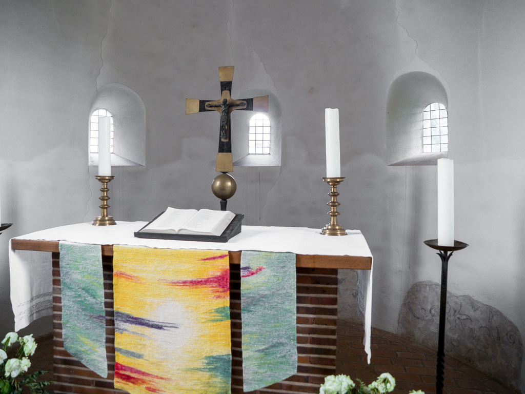 Die drei originalen Rundbogenfenster der Apsis. Mit dem Altar ergibt sich ein Bild von schlichter Anmut.